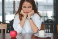 Upset Asian woman choosing between apple or unhealthy cake on the desk. Healthy lifestyle and dieting concept. Selective focus an Royalty Free Stock Photo