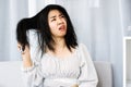 Upset Asian woman using comp brushing her dry ,damaged hair unhappy with messy hair Royalty Free Stock Photo