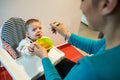 Upset baby eating solid food from a spoon. diversification Royalty Free Stock Photo