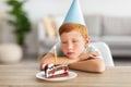 Upset birthday boy looking at lid candle on his cake Royalty Free Stock Photo