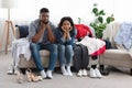 Upset Black Couple Sitting On Couch Beside Old Fashioned Unfitting Clothes