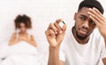 Upset black guy taking potency pill before sex with girlfriend Royalty Free Stock Photo