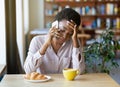 Upset black lady having unpleasant conversation on smartphone during breakfast at city cafe