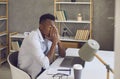 Black man sitting at his office desk feeling tired, overwhelmed and stressed out Royalty Free Stock Photo