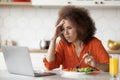 Upset Black Woman Having Breakfast And Using Laptop In Kitchen Royalty Free Stock Photo