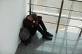 Upset boy with backpack sitting near window indoors Royalty Free Stock Photo