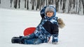 Upset boy fell from the sleds and hurt his head after riding down the snowy hill. Injury and trauma on active winter holiday and Royalty Free Stock Photo