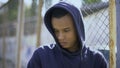 Upset boy leaning on fence, migrant child separated from family and detained