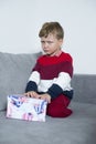 Upset boy sits with a gift on the bed