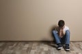 Upset boy sitting on floor at color wall Royalty Free Stock Photo