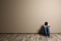 Upset boy sitting on floor at color wall. Royalty Free Stock Photo