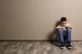 Upset boy sitting on floor at color wall Royalty Free Stock Photo