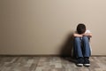 Upset boy sitting on floor at color wall Royalty Free Stock Photo