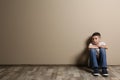 Upset boy sitting on floor at color wall Royalty Free Stock Photo