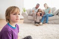 Upset boy sitting on floor while parents enjoying with sister Royalty Free Stock Photo