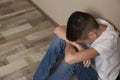 Upset boy sitting on floor at wall Royalty Free Stock Photo