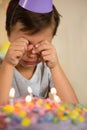 Upset boy sitting in front of birthday cake Royalty Free Stock Photo