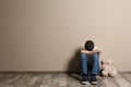 Upset boy with toy sitting on floor at color wall Royalty Free Stock Photo