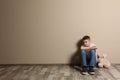 Upset boy with toy sitting on floor at color wall Royalty Free Stock Photo