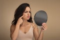 Upset brunette young woman looking at mirror and touching her face Royalty Free Stock Photo