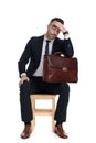 Upset businessman holding briefcase and hand on head, thinking