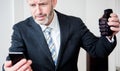 Upset businessman looking at phone and holding a hand grenade Royalty Free Stock Photo