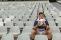 Upset Caucasian male rugby player sitting with rugby ball in stadium