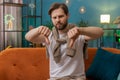 Upset Caucasian man showing thumbs down, dislike bad work, disapproval dissatisfied feedback at home Royalty Free Stock Photo