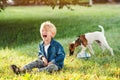 Upset child boy at the summer park. Childhood. Sad kid walking with dog. Little boy crying and sitting on the ground Royalty Free Stock Photo