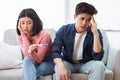 Upset Child-Free Chinese Couple Holding Positive Pregnancy Test Sitting Indoors