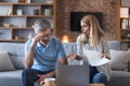 Upset confused adult european husband and wife pay taxes with laptop, suffer from stress and pressure Royalty Free Stock Photo