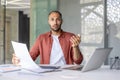 Upset and confused man looking at camera while working inside office with documents, papers and reports. Paperwork Royalty Free Stock Photo