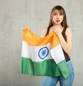 Portrait of young woman with sad expression on face standing against gray wall with national flag of India Royalty Free Stock Photo