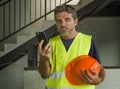 Upset construction worker or stressed contractor man in hardhat and vest talking on mobile phone unhappy in stress messing with