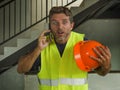 Upset construction worker or stressed contractor man in hardhat and vest talking on mobile phone unhappy in stress messing with Royalty Free Stock Photo