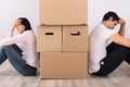 Upset Couple Sitting Back To Back Behind The Boxes Royalty Free Stock Photo