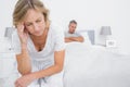 Upset couple sitting on opposite ends of bed after a fight