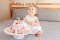 upset crying Caucasian blonde baby girl in white dress celebrating her first birthday