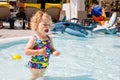 Upset crying little toddler girl in the swimming pool on family vacations in a hotel resort. Sad child playing in water