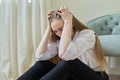 Upset crying young woman sitting at home on the floor.