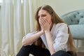 Upset crying young woman sitting at home on the floor.