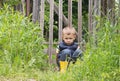 Upset cute little boy sitting on the background of a rustic wooden fence and is sad Royalty Free Stock Photo