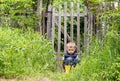 Upset cute little boy sitting on the background of a rustic wooden fence and is sad Royalty Free Stock Photo