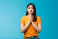 Upset cute silly asian girl praying, plead for help, pouting frowning need, make pitty face, hold hands pray begging for Royalty Free Stock Photo