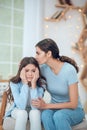 Upset daughter and caring mom sitting at home