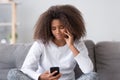 Upset depressed african teen girl looking at phone at home Royalty Free Stock Photo