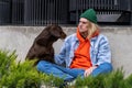 Upset depressed millennial guy sociopath sitting on ground outdoors with his dog Royalty Free Stock Photo