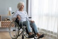 Upset disabled older woman sitting in wheelchair, looking out window Royalty Free Stock Photo