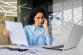 Upset and disappointed businesswoman behind paperwork, financier checking papers, contracts, documents and reports