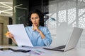 Upset and disappointed woman behind paperwork, hispanic woman reading and checking financial report, financial